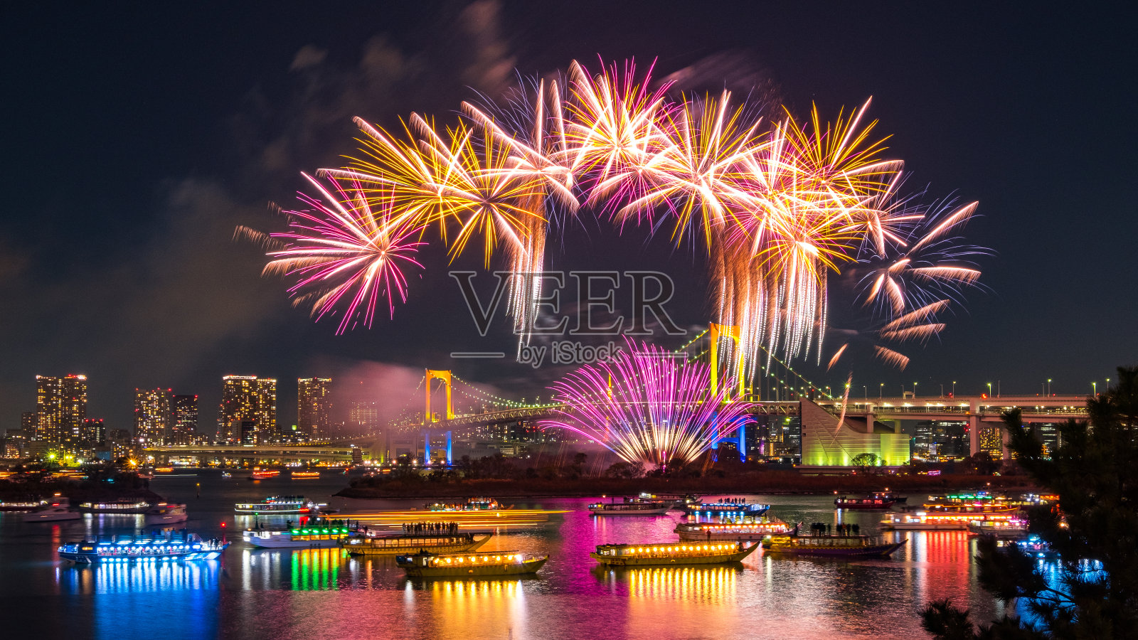 彩虹桥和东京塔的空中天际线在晚上,河里有许多点亮的船只和壮观的冬季烟花。照片摄影图片
