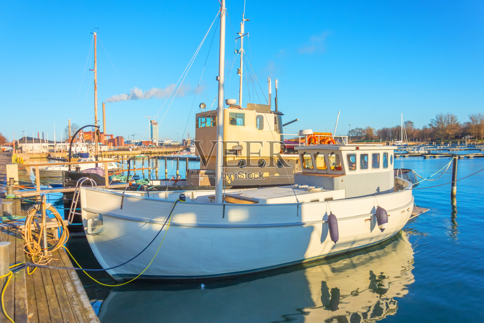 在一个晴朗晴朗的日子里,小船停靠在城市的码头上。照片摄影图片