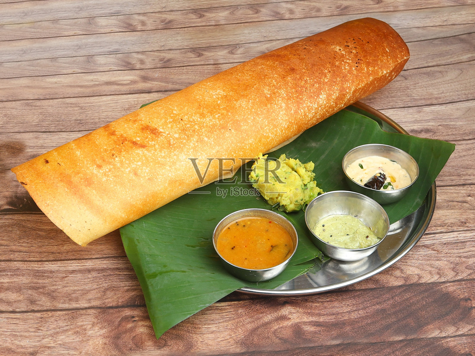 马萨拉薄饼(Masala dosa)是南印度的一种传统薄饼,馅料是土豆泥和炸洋葱的混合物,配上酸辣酱和印度酸辣酱照片摄影图片