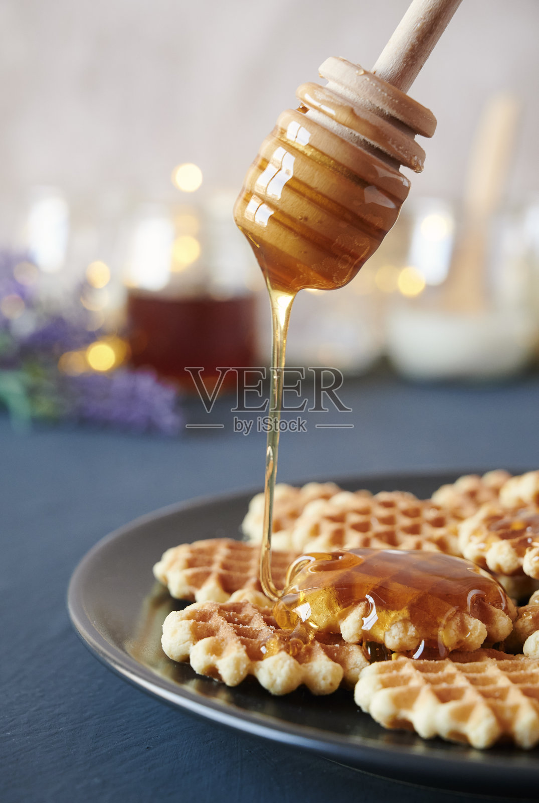 把蜂蜜倒在一盘刚烤好的华夫饼上,近景照片摄影图片