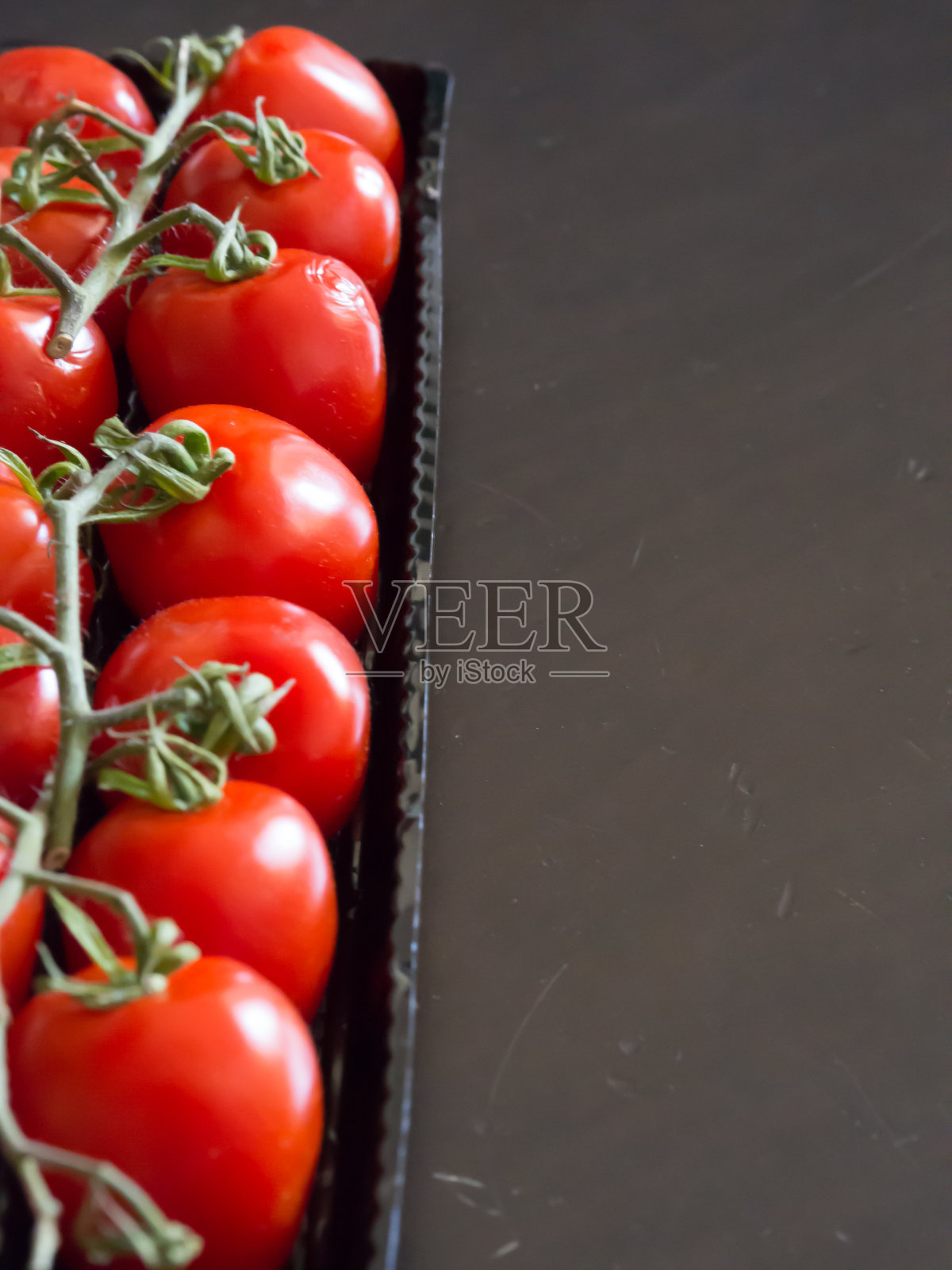 一行红色番茄与黑色背景和复制空间。生态系统概念照片摄影图片