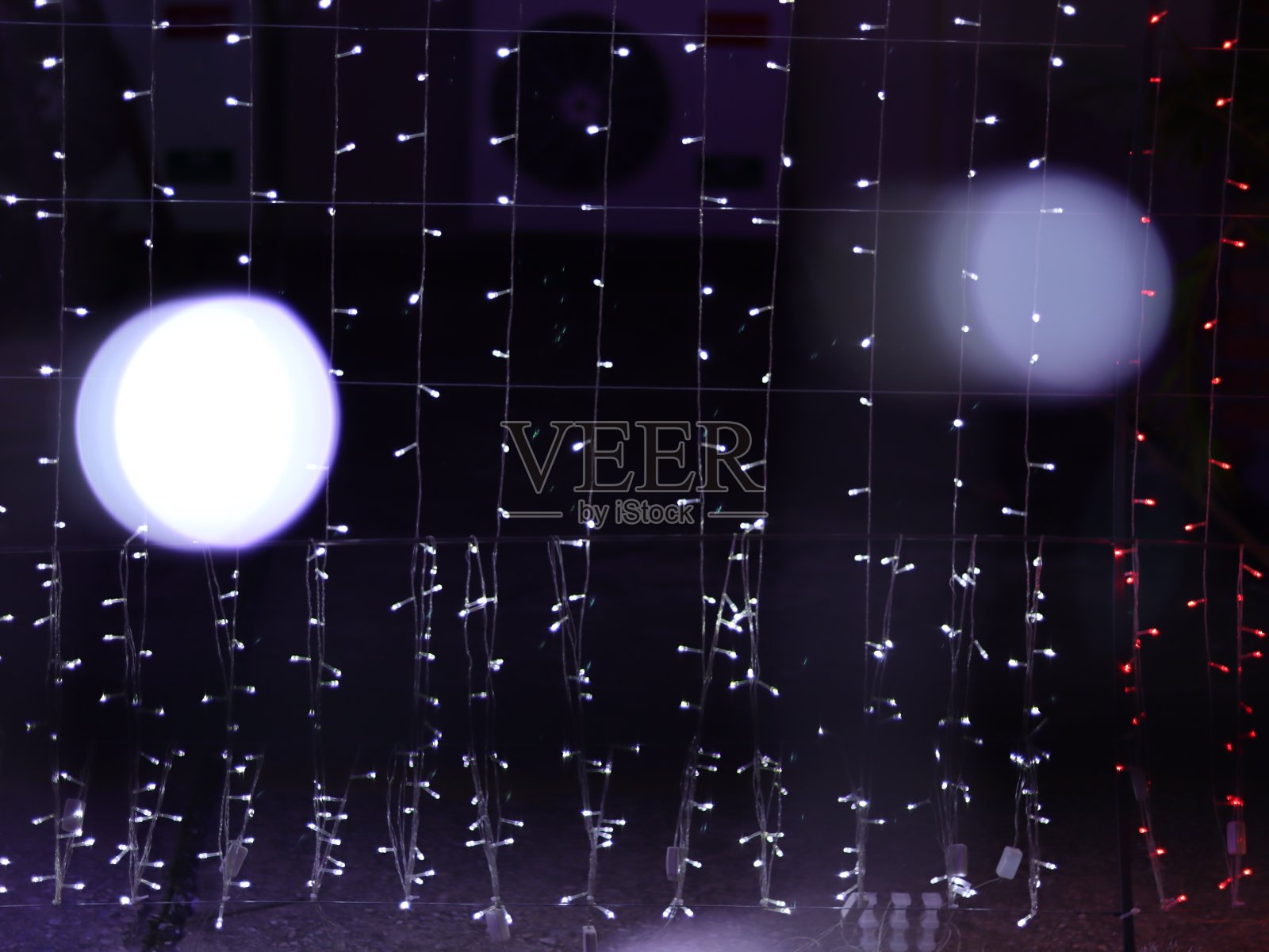 摘要散景灯模糊了背景,圣诞树上的灯泡为庆祝季节用粉色、紫色和白色的彩色散焦圈作为背景邀请卡。多色彩虹散景。照片摄影图片