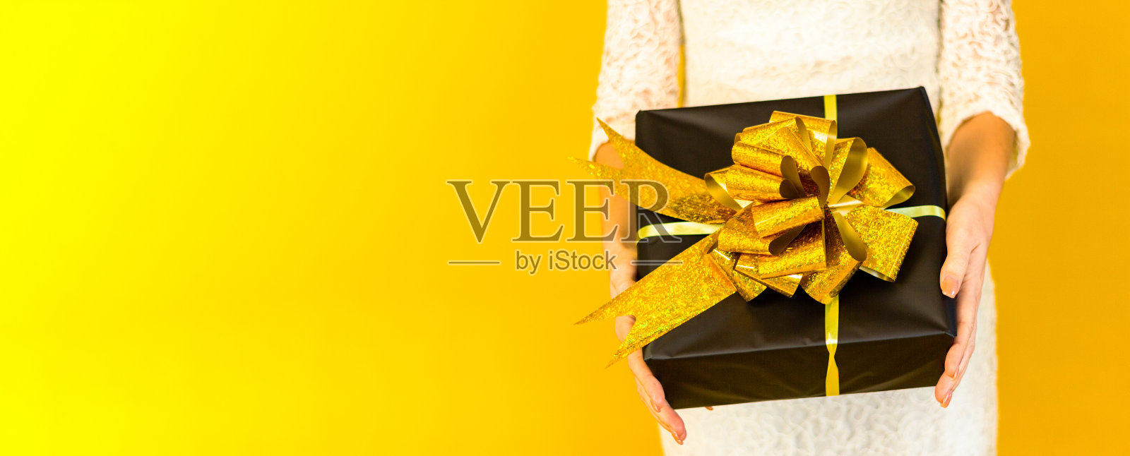宽横幅。女性双手在服装上拿着礼盒拷贝空间黄色背景,庆祝销售概念妇女节和礼品照片摄影图片