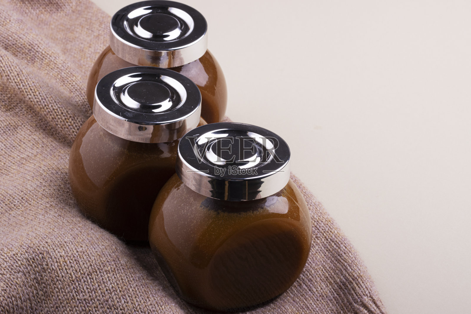 甜美柔嫩的自制焦糖在一个玻璃罐上柔软的羊毛表面,俯视图照片摄影图片