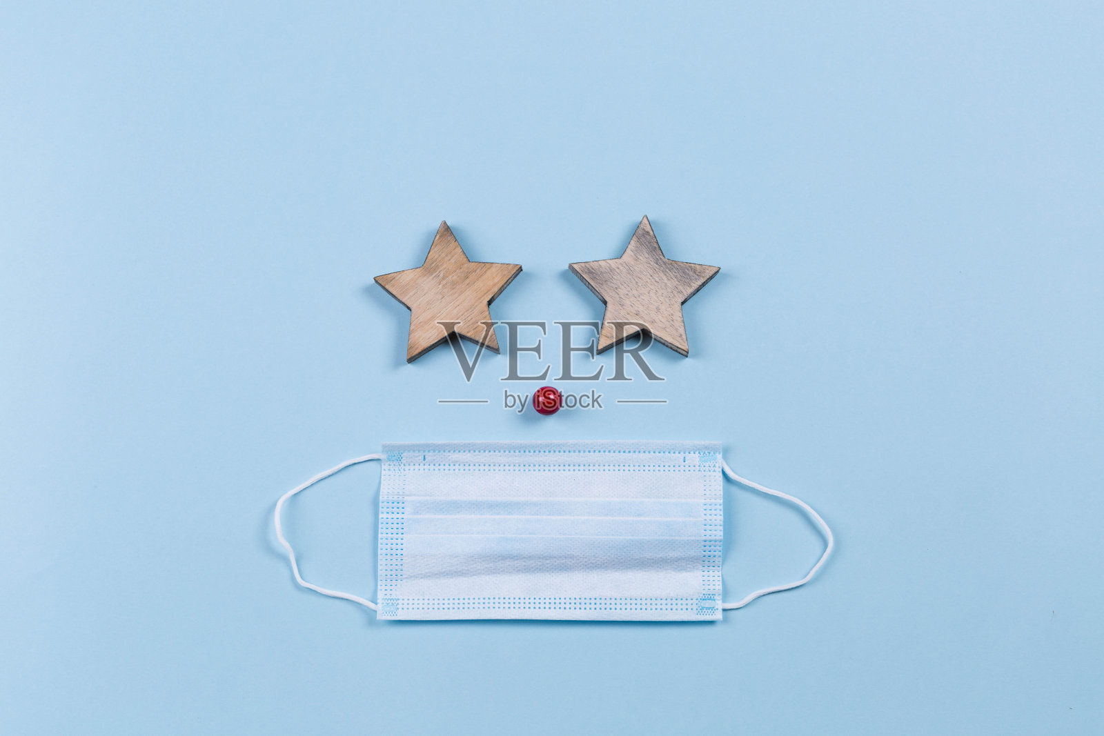 蓝色背景下的冠状病毒防护面具,圣诞装饰,迷迭香树枝,红浆果,木制星星和树叶,复制空间照片摄影图片