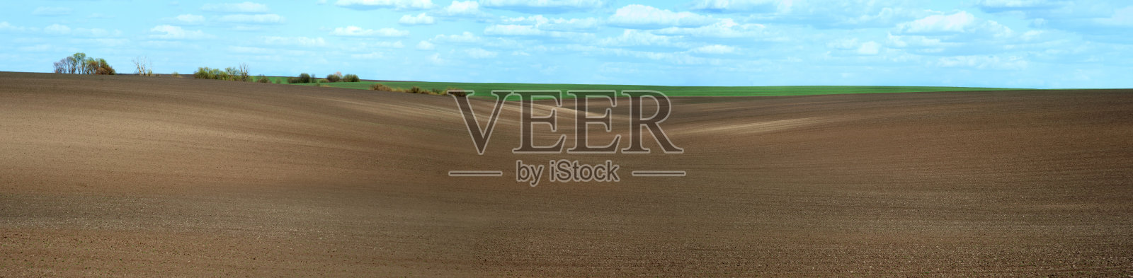 春季多云的丘陵地形上播种田线全景图照片摄影图片