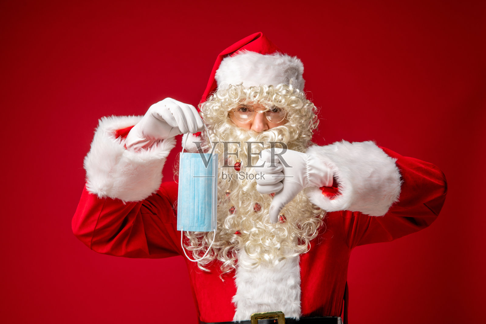 圣诞老人拿着保护面罩,显示拇指向下。照片摄影图片