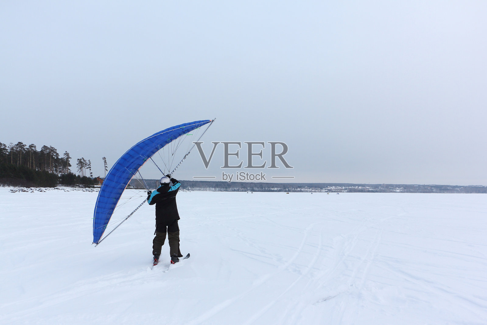 冬季,俄罗斯新西伯利亚鄂毕河水库,一名男子在结冰的河流上带着风筝训练照片摄影图片