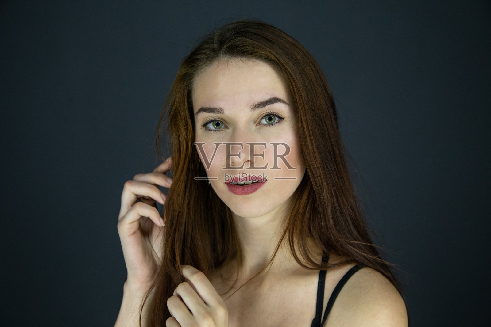 年轻的黑发女孩的肖像与长头发在黑色的背景照片摄影图片