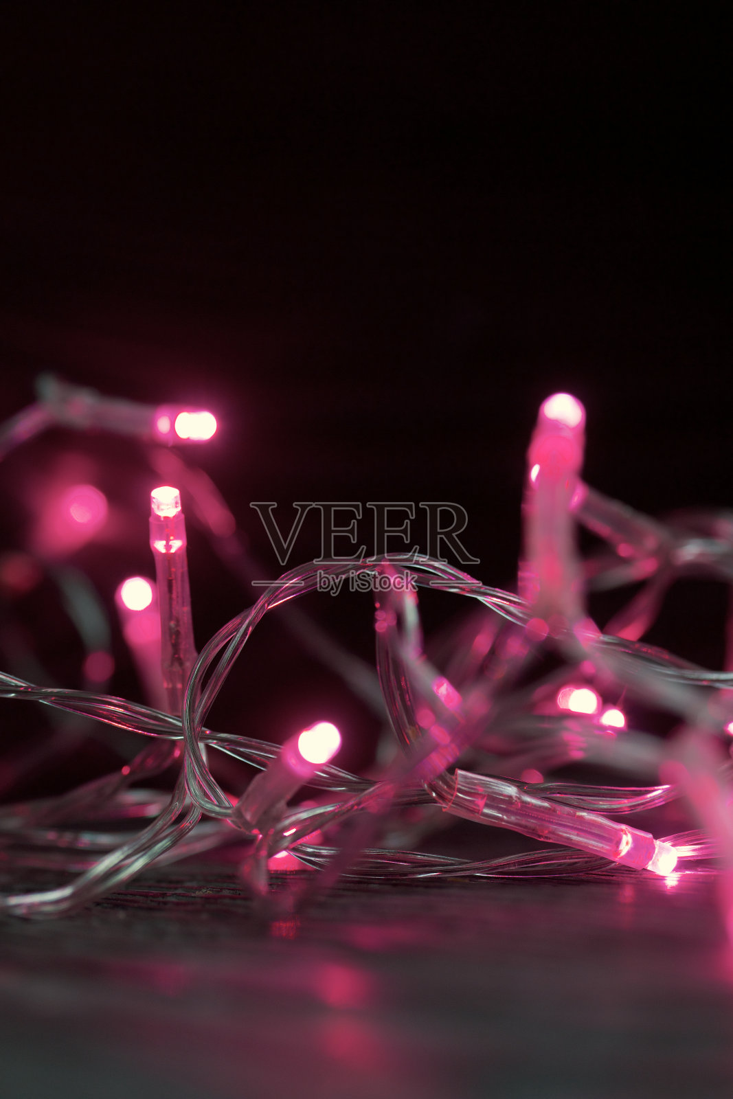 燃烧着粉红色灯光的花环。在黑暗中燃烧。特写镜头。照片摄影图片