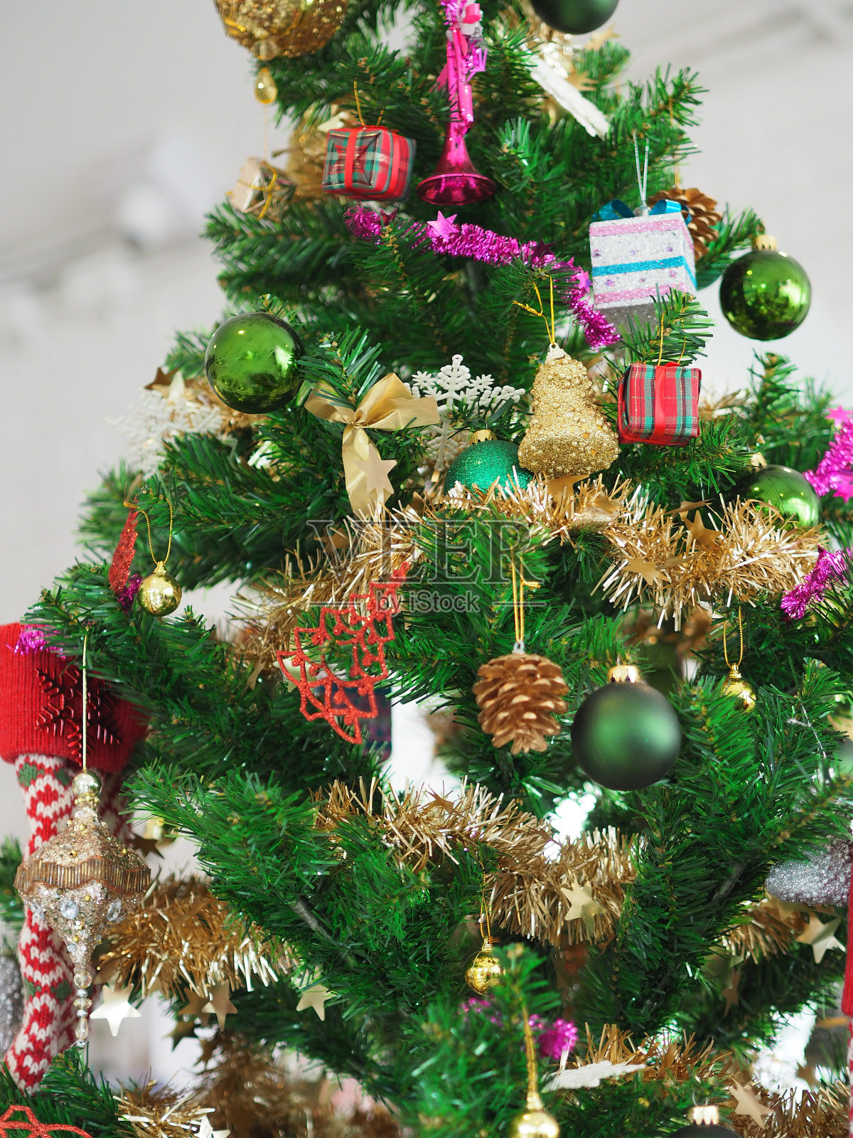 圣诞装饰品绿色的树挂,金色的礼盒,绿色的球,棕色的松果,袜子,鞋子,粉红色的铃铛包裹在白色的背景金色缎带照片摄影图片