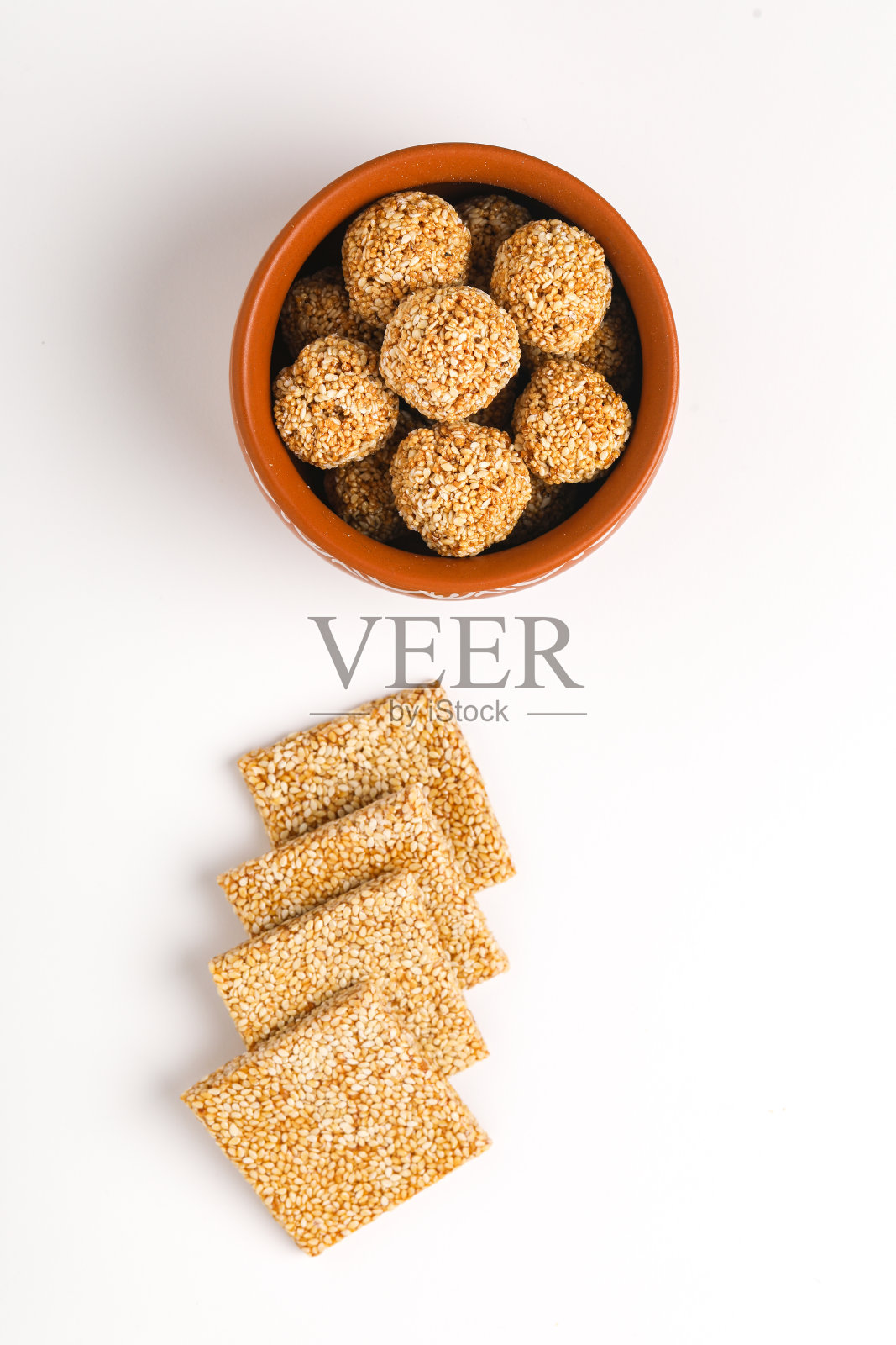 白色背景上的芝麻丸子是印度的一道甜食,由粗糖和芝麻做成。照片摄影图片