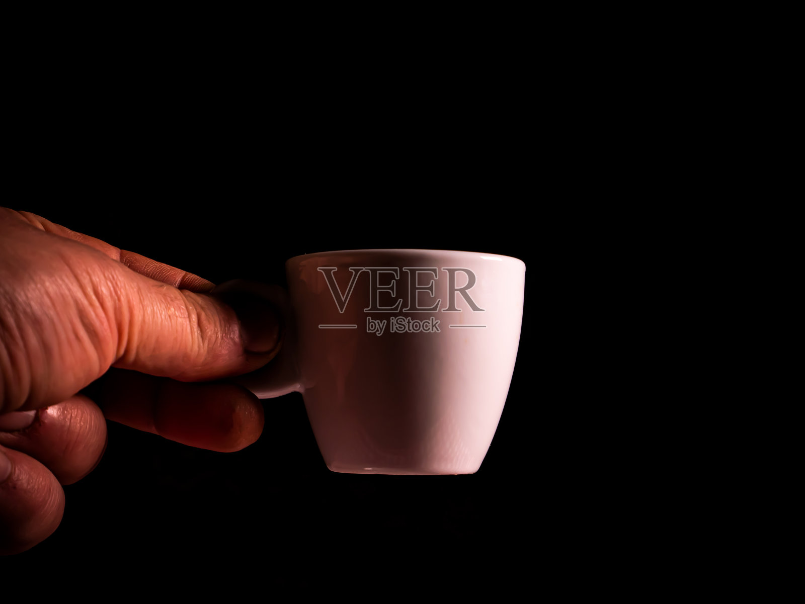 黑色背景上拿着咖啡杯。照片摄影图片