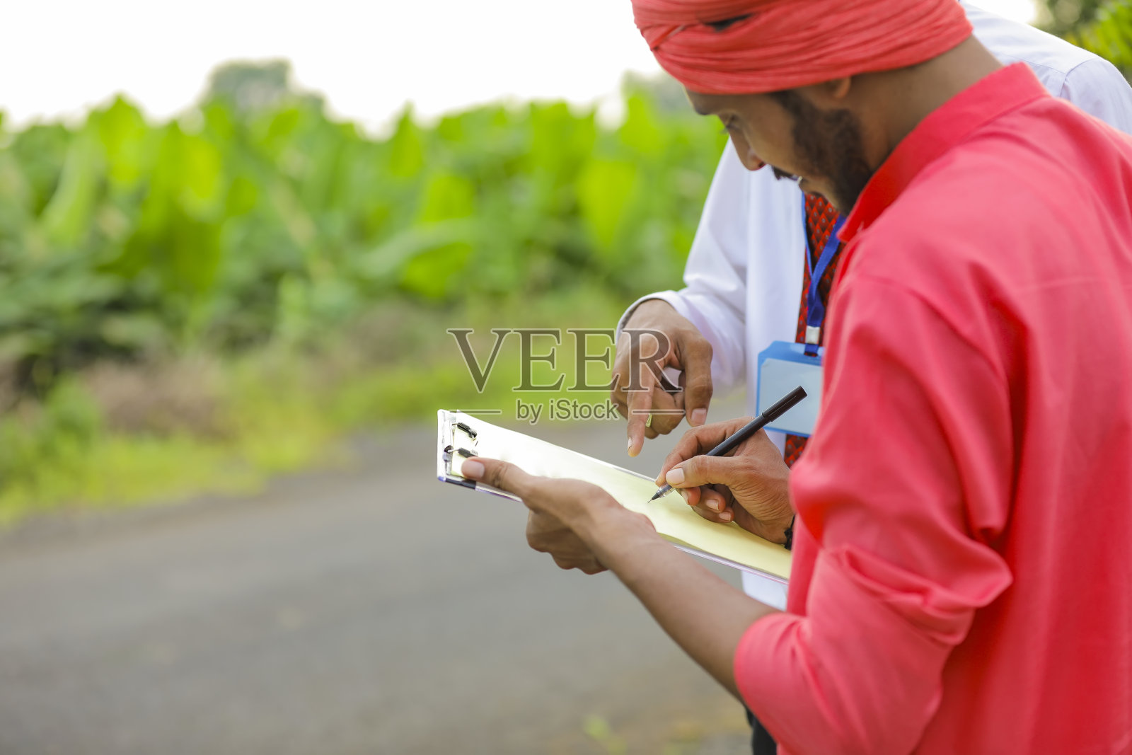 年轻的印度农民在农业区与银行家签署文件照片摄影图片