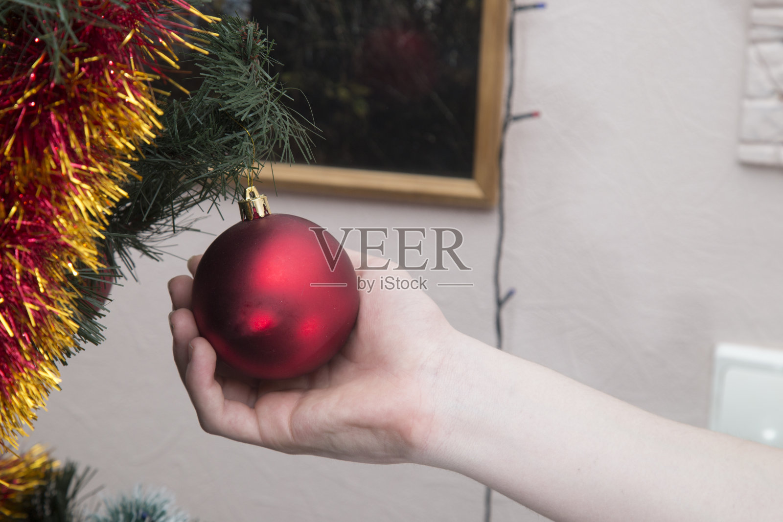 一个男人用圣诞玩具装扮圣诞树。照片摄影图片