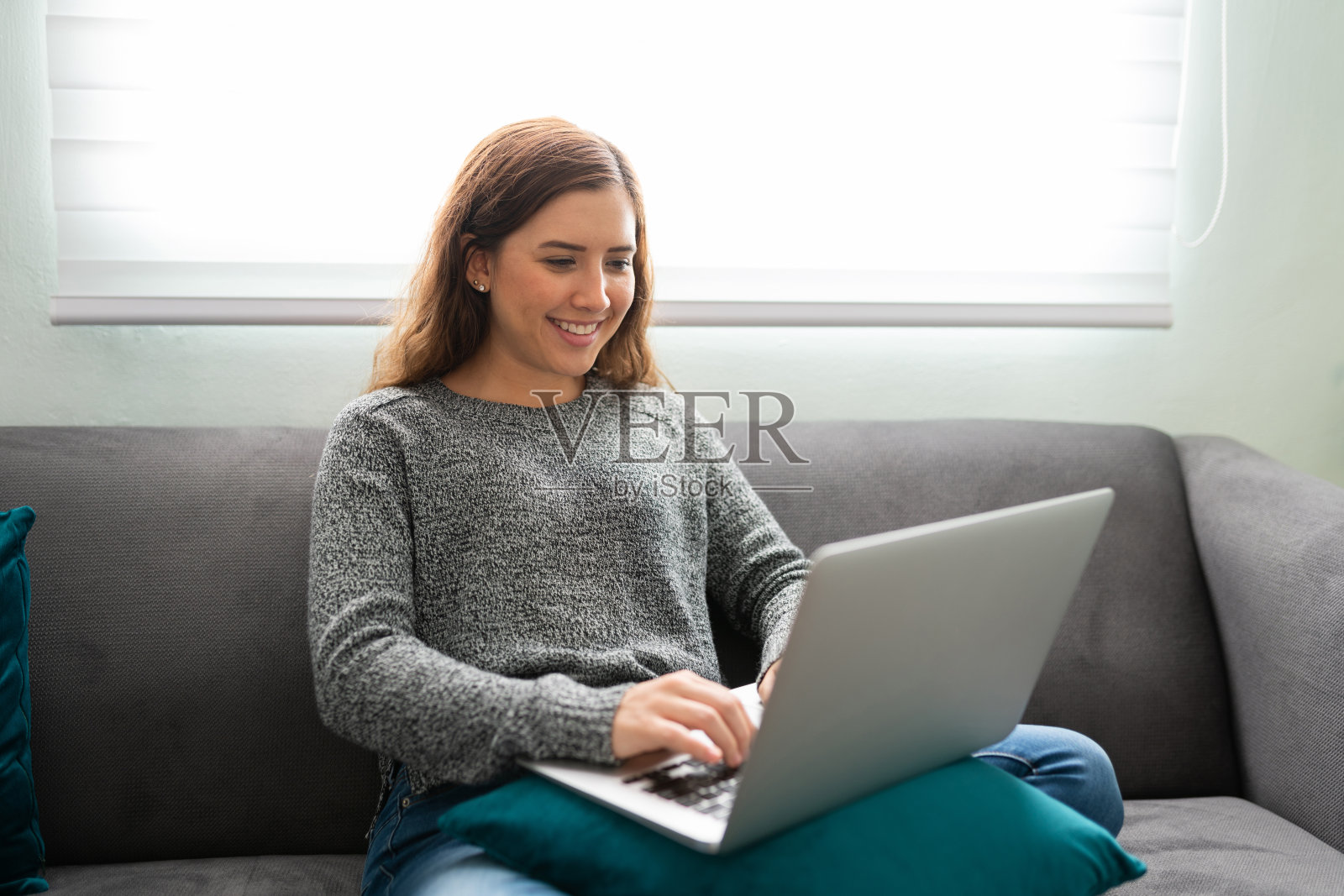 在沙发上用笔记本电脑的快乐女人照片摄影图片