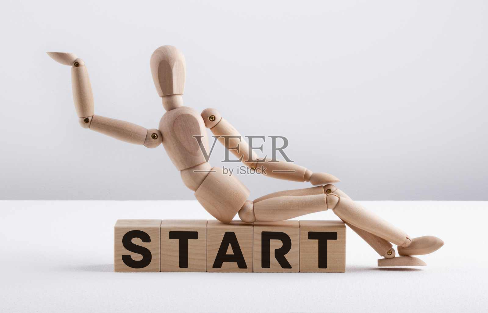 木头人坐在木头方块上写着START。经营理念。照片摄影图片