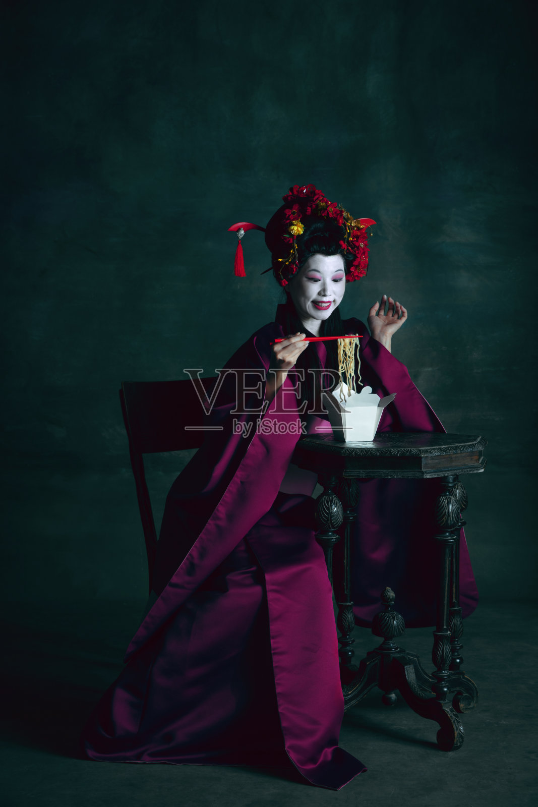 年轻的日本女人作为艺妓在深绿色的背景。复古风格,比较时代的概念。照片摄影图片