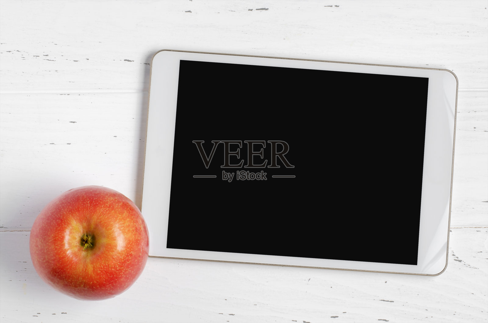 一个空屏幕和苹果在白色木制背景上的平板电脑。为学校儿童或在线学习的概念应用程序。本空间照片摄影图片