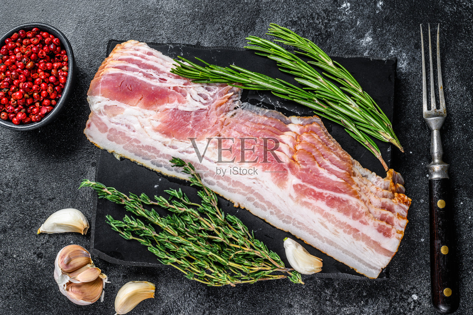 准备烹调的切成薄片的生猪肉培根。黑色背景。俯视图照片摄影图片