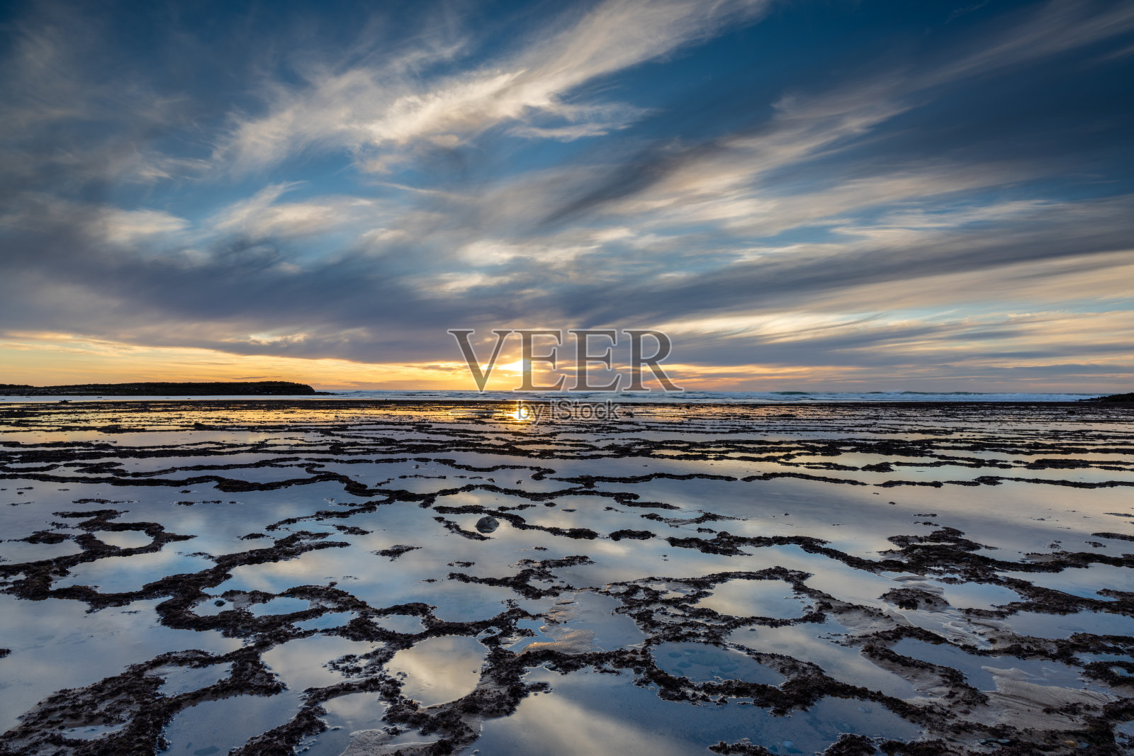 美丽的日落与岩石海滩和潮汐池在前景照片摄影图片
