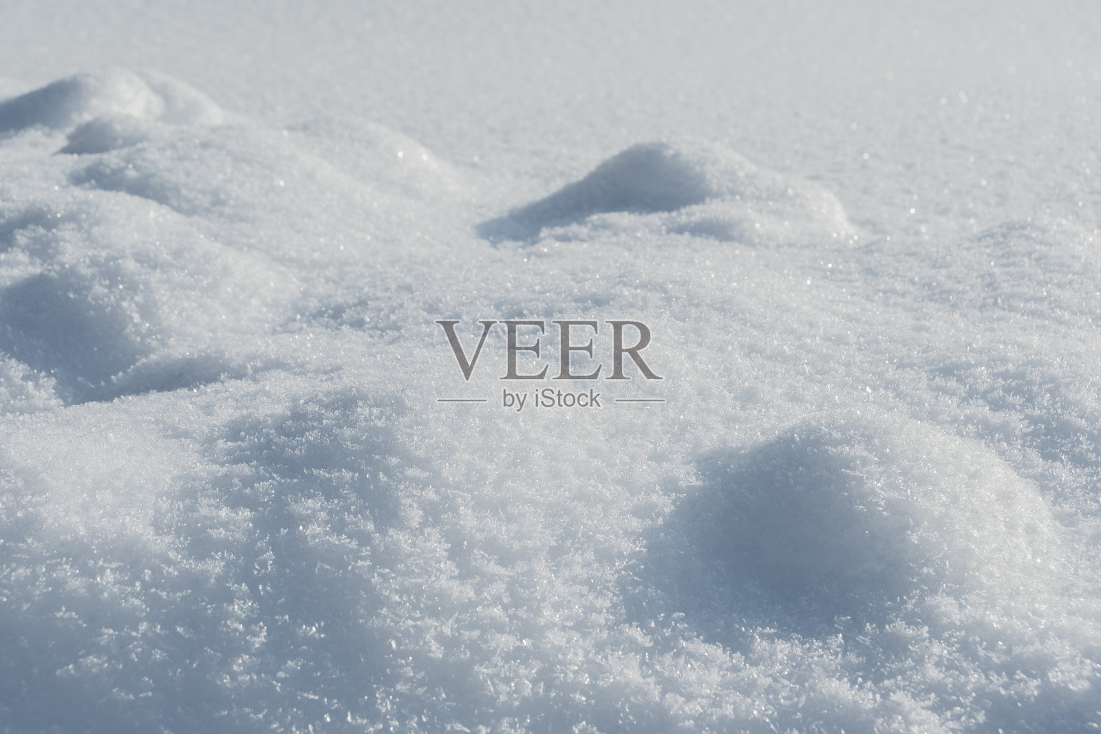 在阳光明媚的冬日,平滑的积雪堆积起来。深而高的积雪被阳光照亮,处于阴影中照片摄影图片