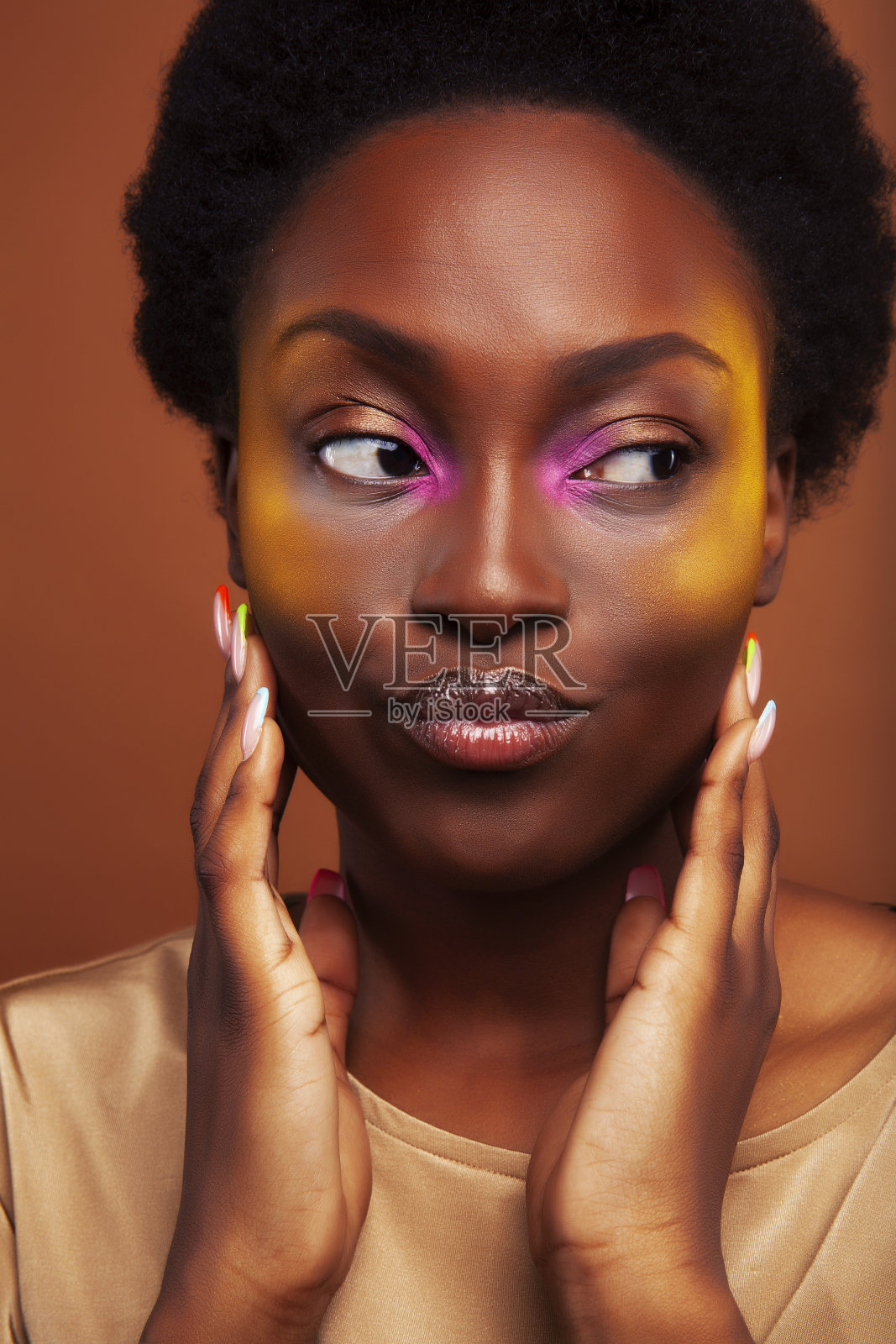 漂亮的年轻的非洲裔美国女人与卷曲的头发摆出愉快的手势在棕色的背景,生活方式的人的概念照片摄影图片