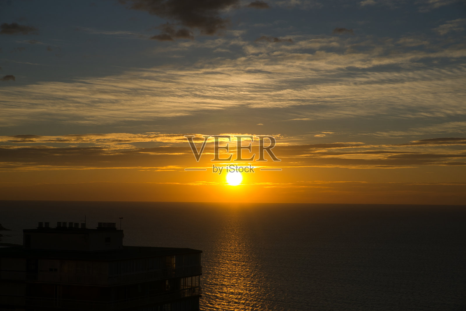 美丽的日出在海上从城市看与云彩照片摄影图片