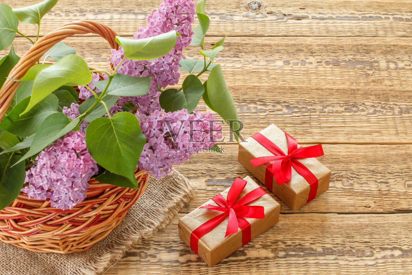 有紫丁香花的柳条篮子和木制的礼盒。照片摄影图片