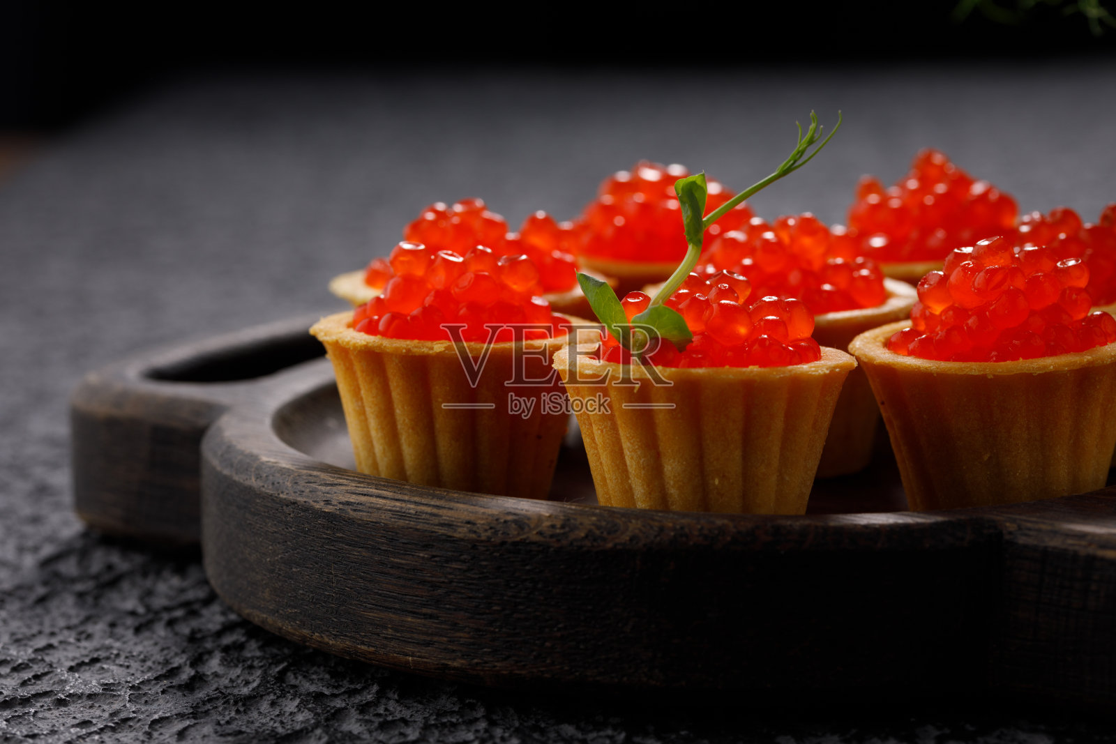 开胃的果馅饼与红鱼子酱在黑色的背景。节日的概念。特写镜头。照片摄影图片