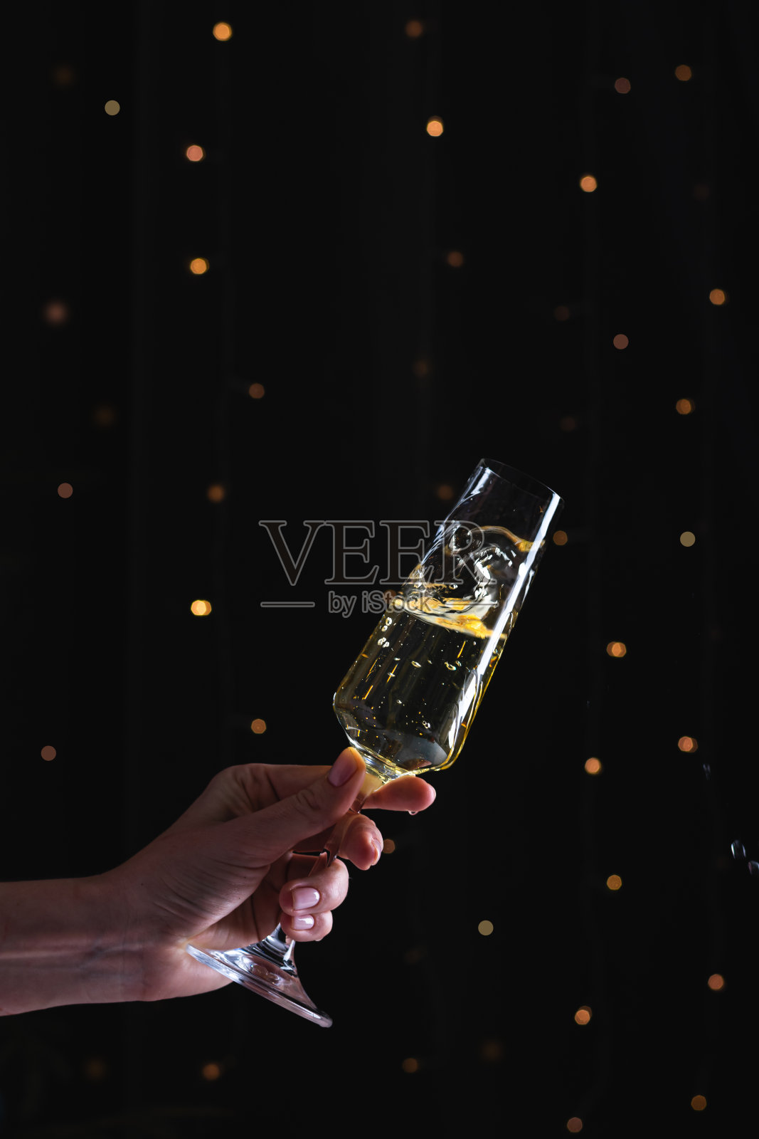 女人手里拿着香槟,背景是黑色的散焦照片摄影图片
