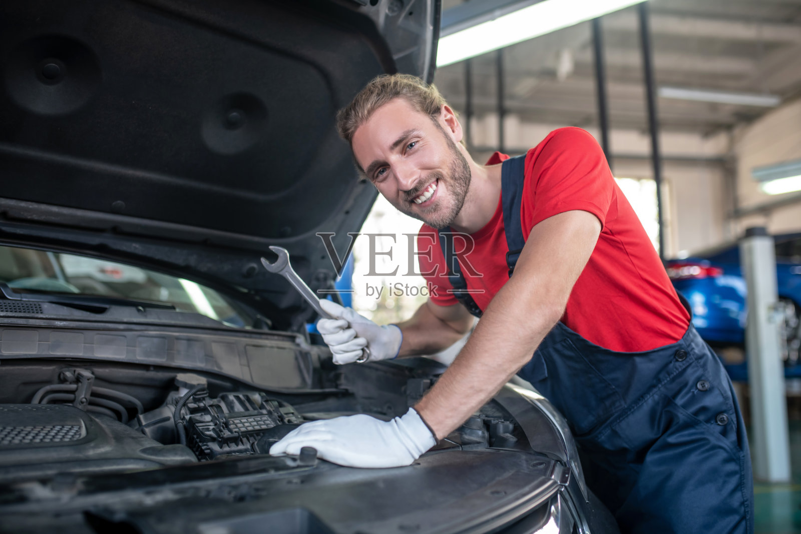 带着扳手微笑的男人靠近汽车引擎盖照片摄影图片