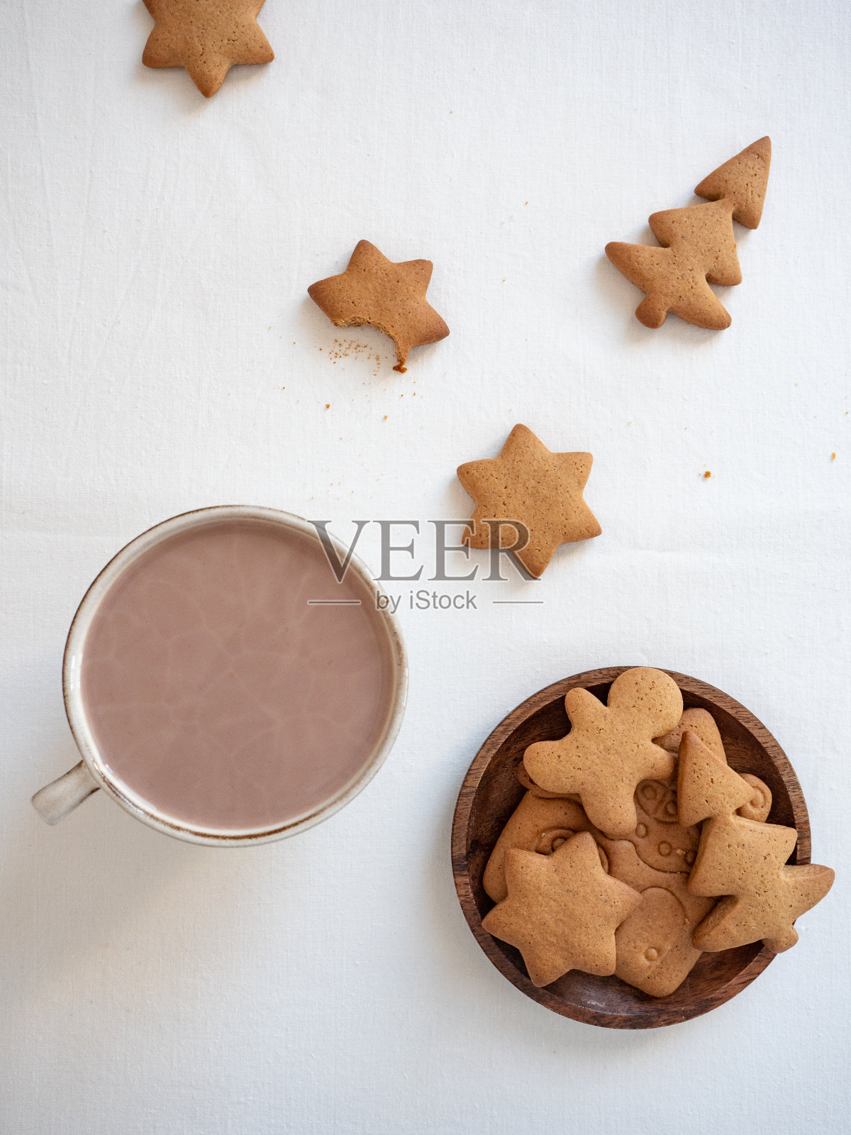 在晨光中,白色的桌子上放着不同形状的姜饼,木盘里放着一杯可可,俯视图照片摄影图片