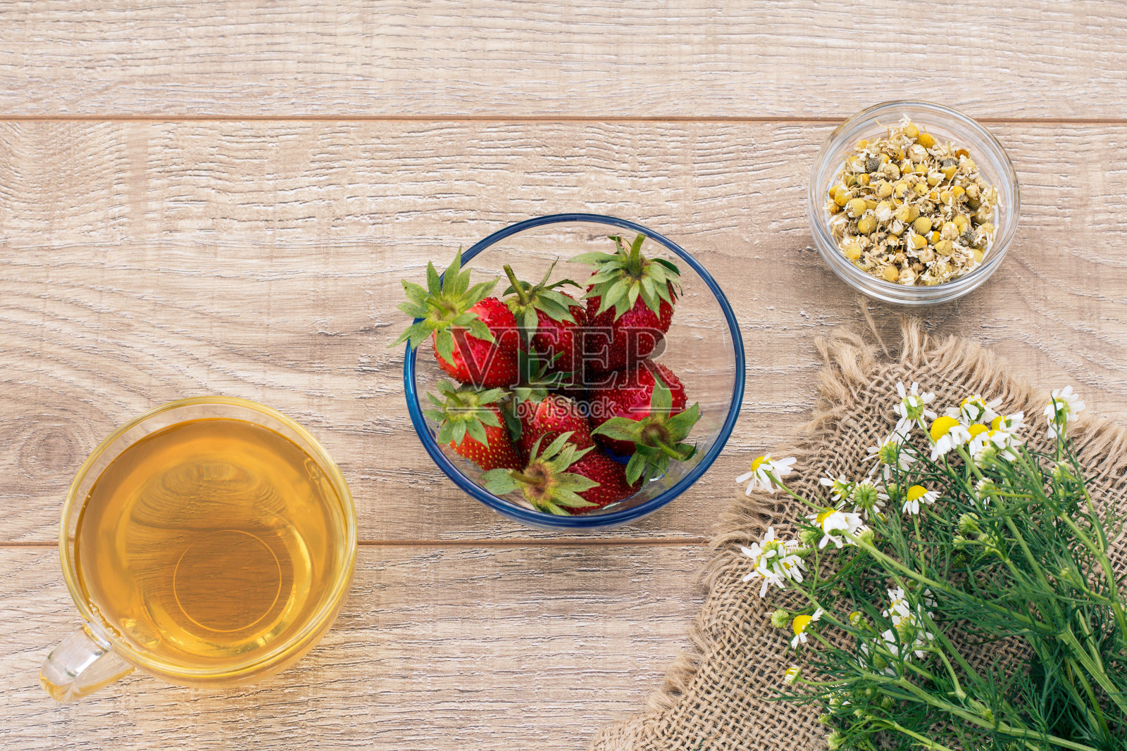 一杯绿茶,草莓和白色的洋甘菊花在木制的背景。照片摄影图片