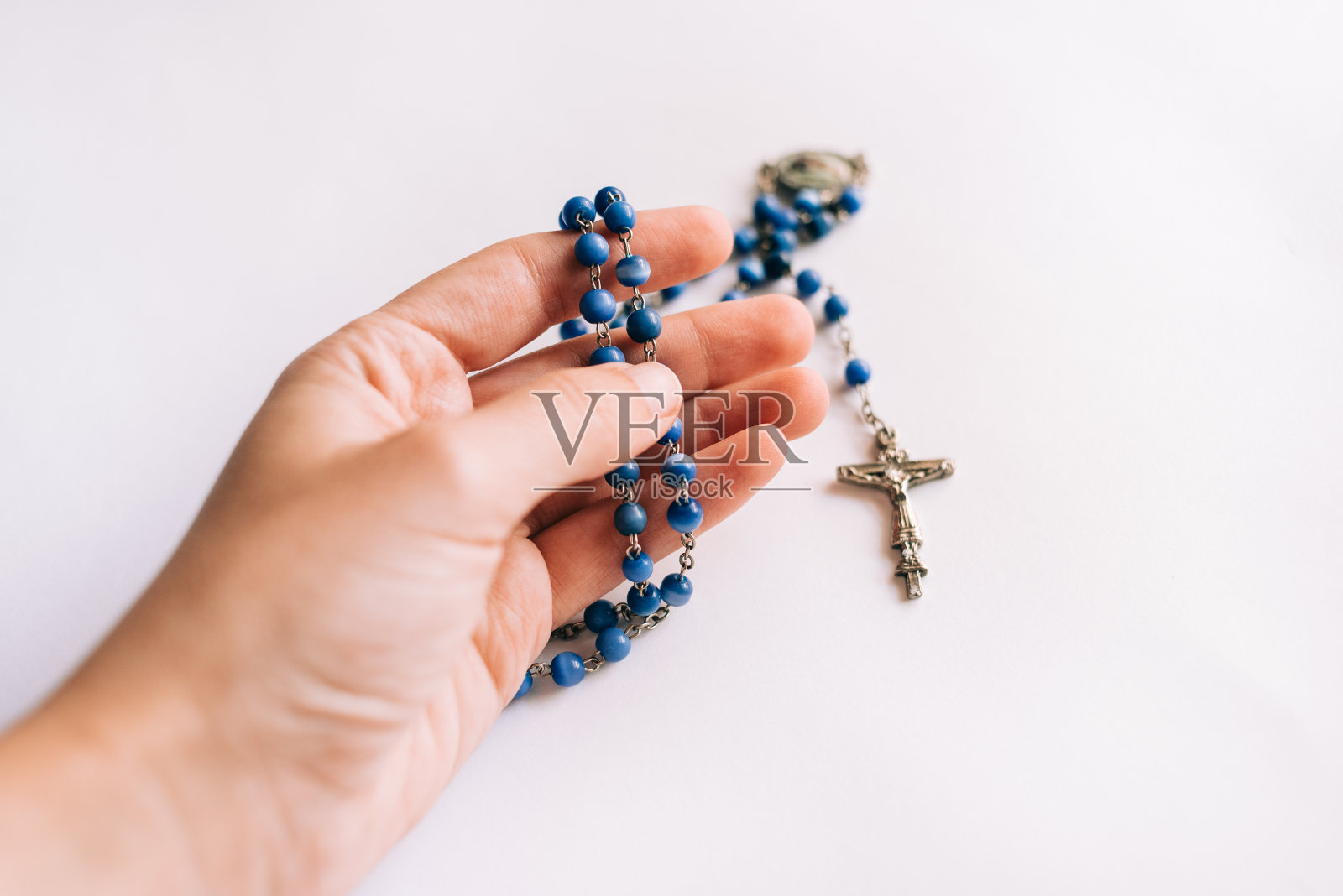 在白色的背景上,一只手拿着念珠照片摄影图片
