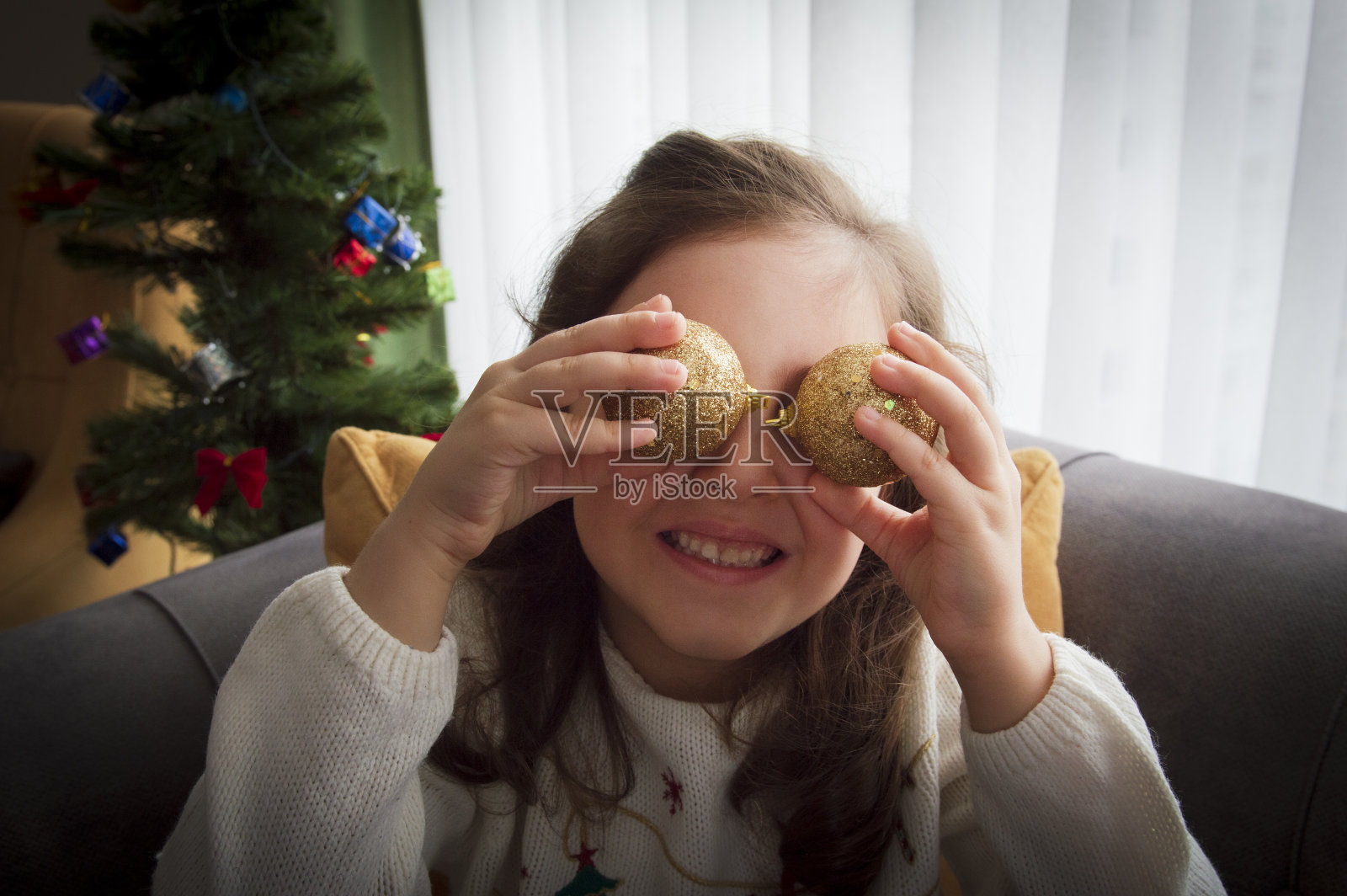 可爱的小女孩在为圣诞树玩球照片摄影图片