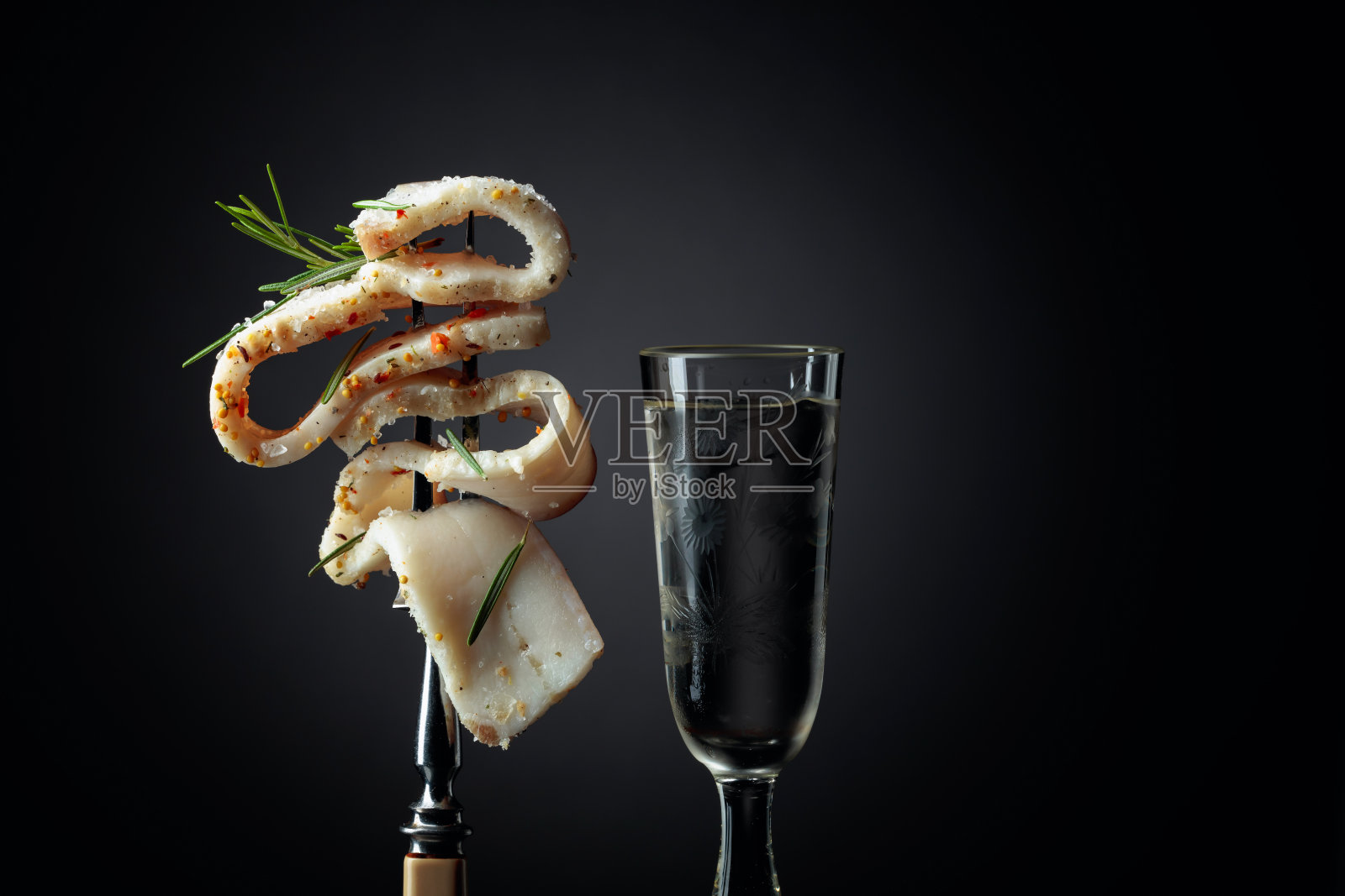 冰冻的玻璃杯,加冰伏特加和一片辛辣的咸猪油。照片摄影图片