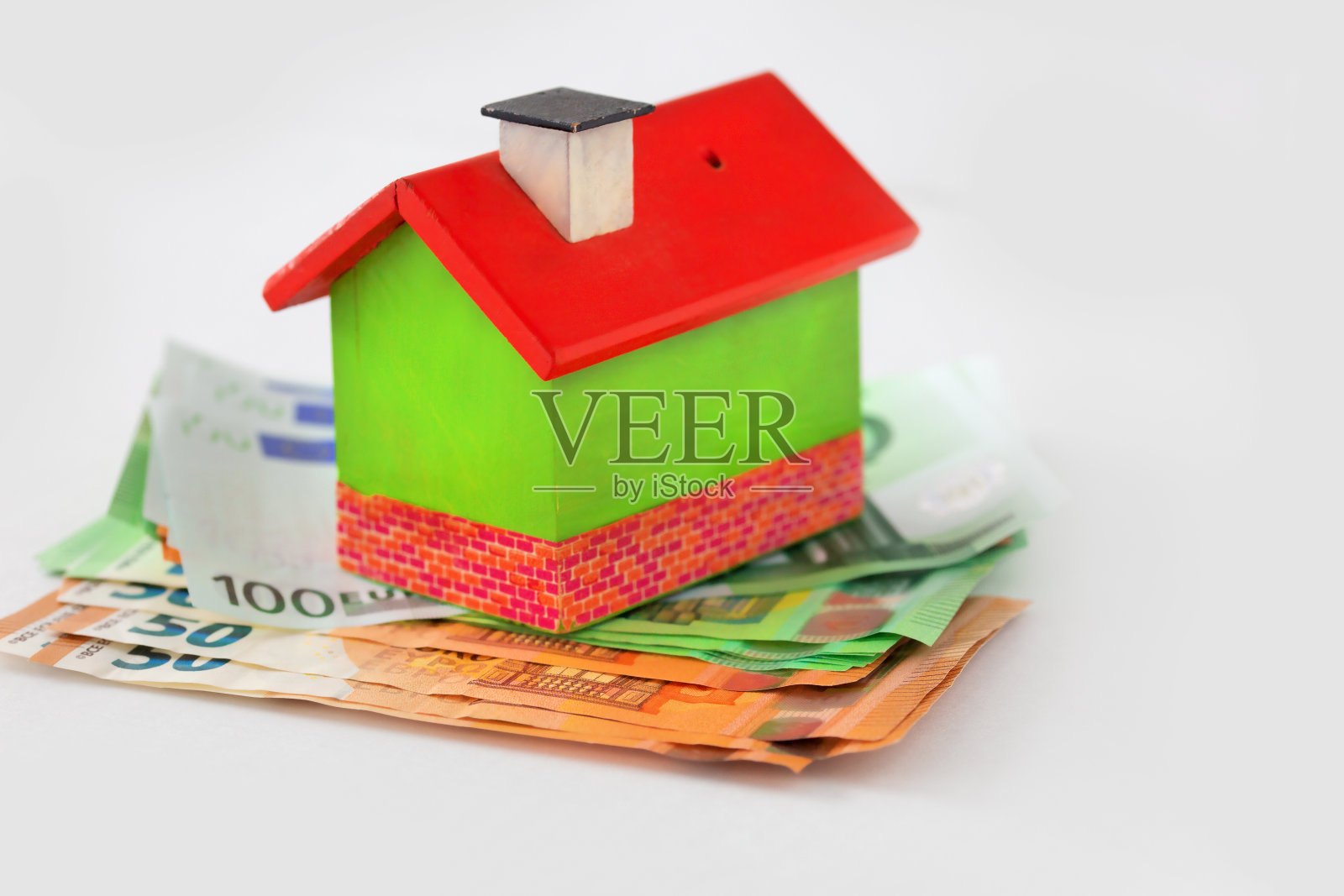 绿色木房子站在钱在一个白色的背景与复制空间。融资和计划。照片摄影图片