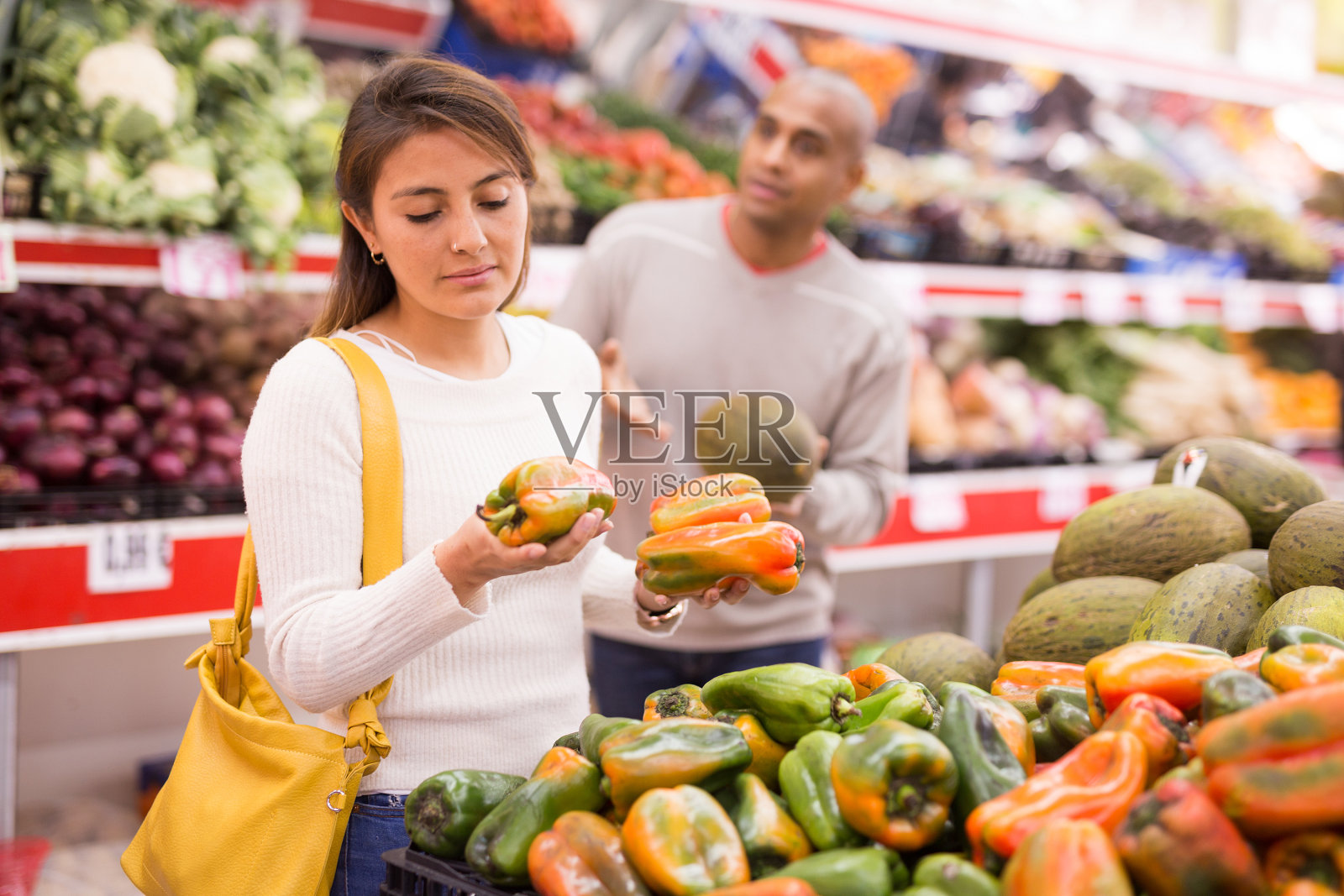 在超市和男友一起挑选甜椒的年轻拉丁美洲女孩照片摄影图片