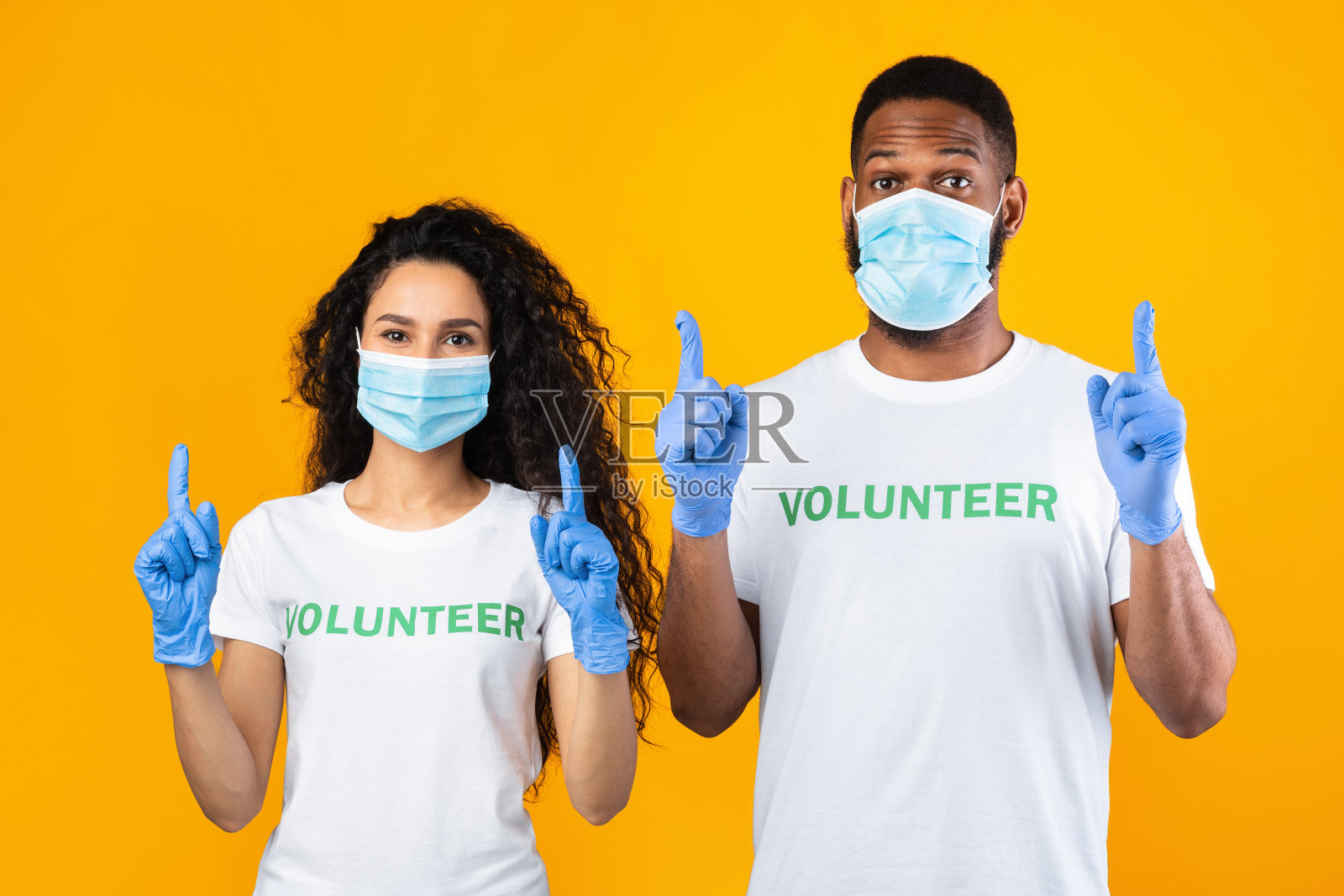 志愿者戴着口罩和手套,手指向上,摄影照片摄影图片