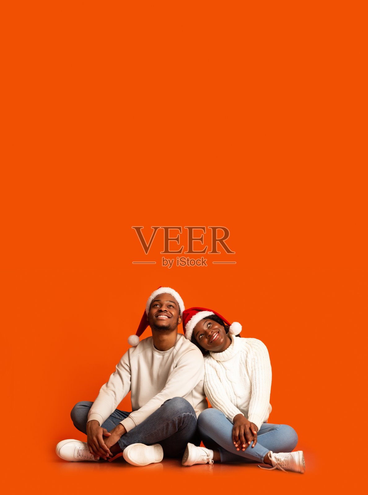 戴着圣诞帽的黑人夫妇坐着向上看拷贝空间照片摄影图片