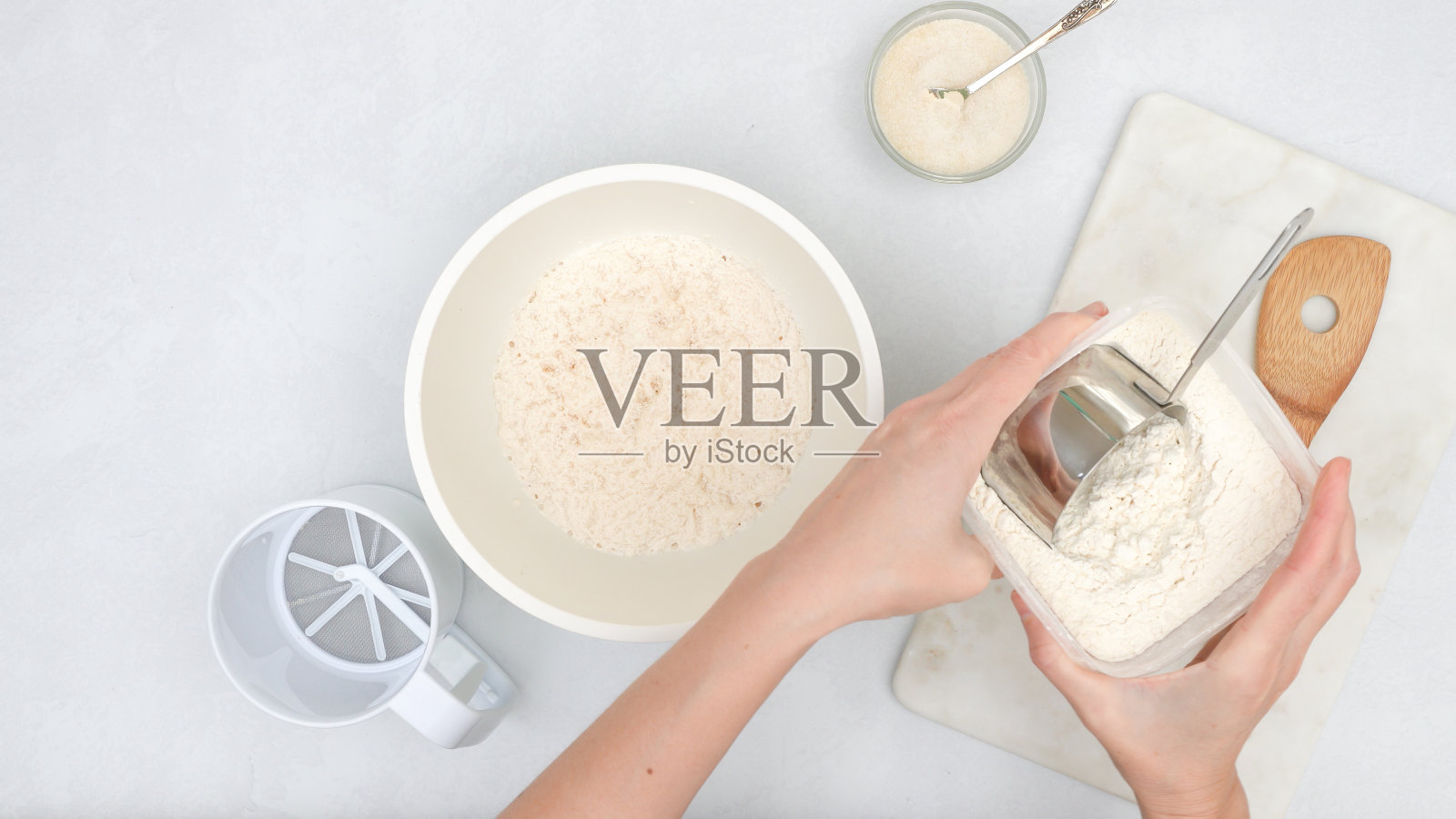 将发酵剂和面粉放入碗中搅拌。一步一步的面包面团食谱,从上面近距离观看,女人的双手照片摄影图片