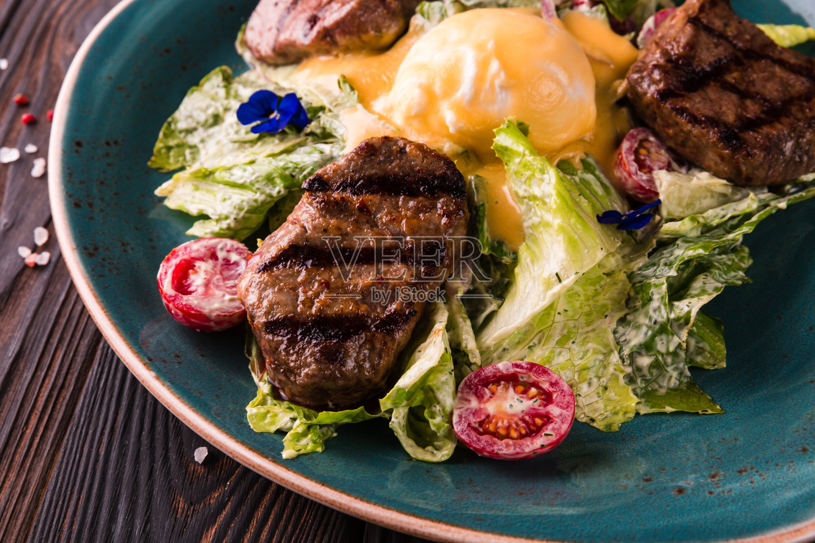 蛋本尼迪克特与牛肉在一个大的白色盘子。传统英式早餐有蛋本尼迪克特,樱桃番茄,生菜。本尼迪克特蛋在餐厅的餐桌背景。照片摄影图片