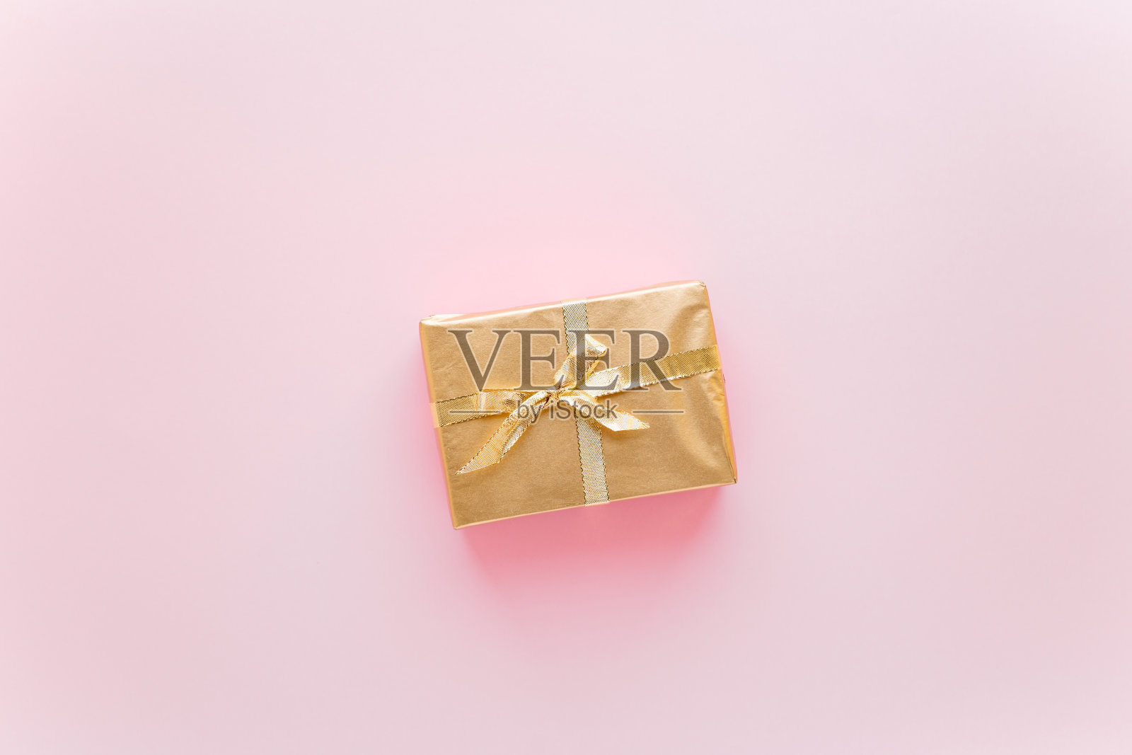 粉红色的圣诞或新年背景,朴素的金色圣诞礼物组成。Flatlay,空白的问候文字。圣诞节的概念。照片摄影图片