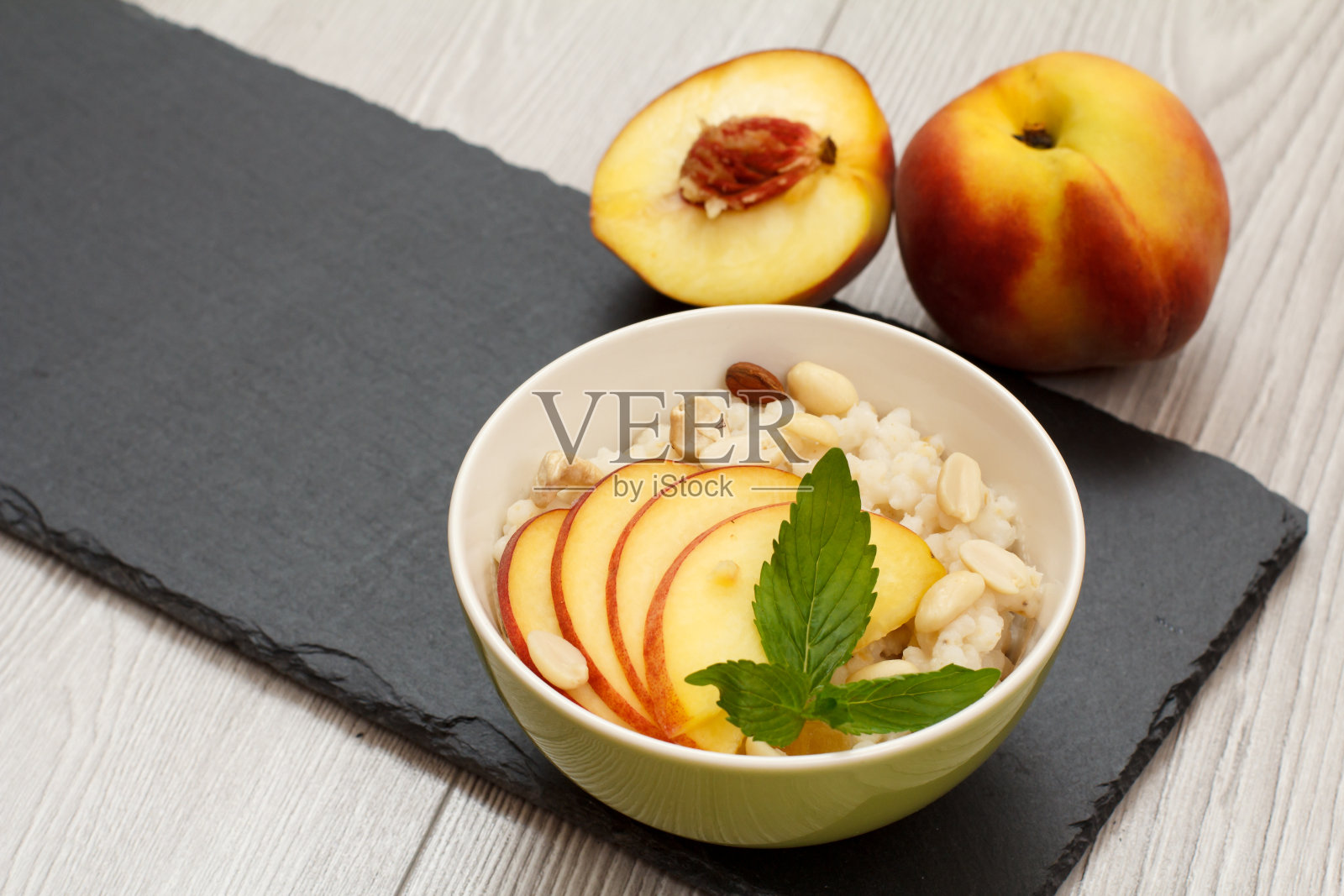 高梁沙拉配果仁和鲜桃在石板上。照片摄影图片