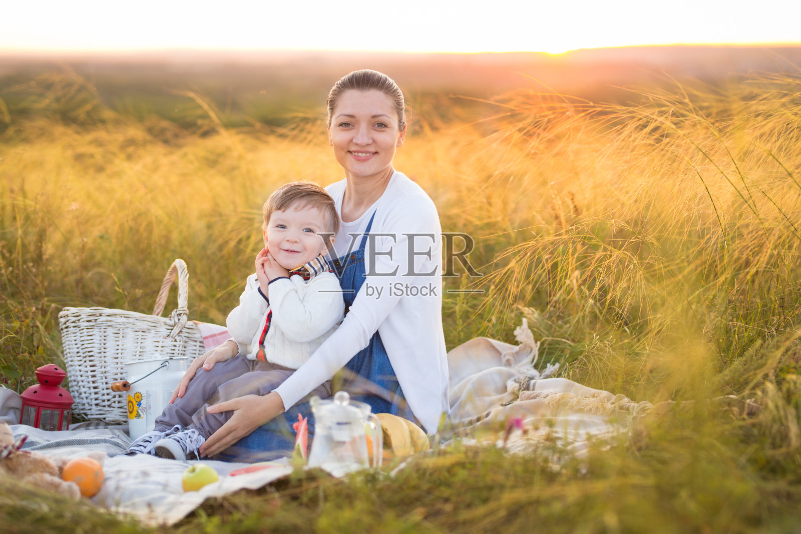 小男孩儿子和怀孕的母亲在野餐照片摄影图片
