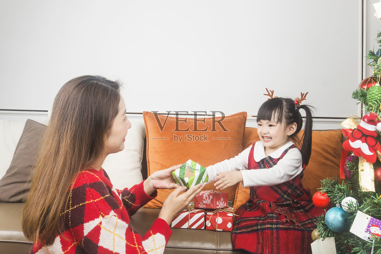 快乐的妈妈和小女儿在家里装饰圣诞树和礼物照片摄影图片