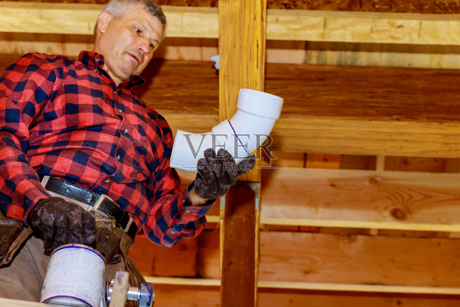水管工用胶水粘白水管,一个安装在新的塑料排水管下施工照片摄影图片