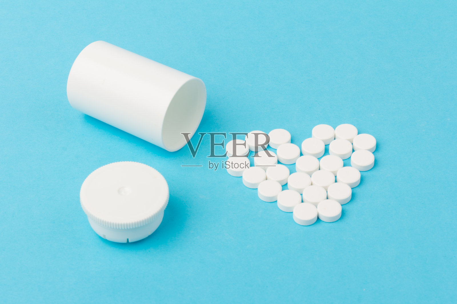 白色药片和瓶中的药片在蓝色背景照片摄影图片