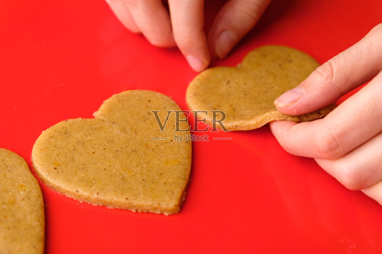 在情人节制作心形饼干,作为女性在红色背景上的礼物照片摄影图片